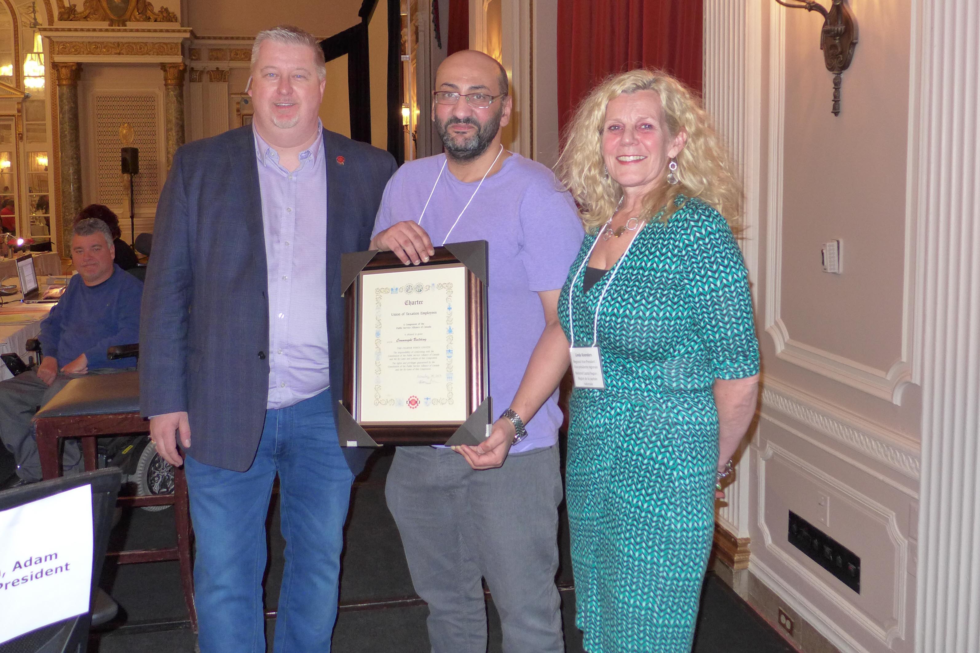 Le président national, Marc Brière et Linda Koenders, VPR pour la RCN, présentent Shady Zekry, président de la section locale 70021 - Édifice Connaught avec la charte locale