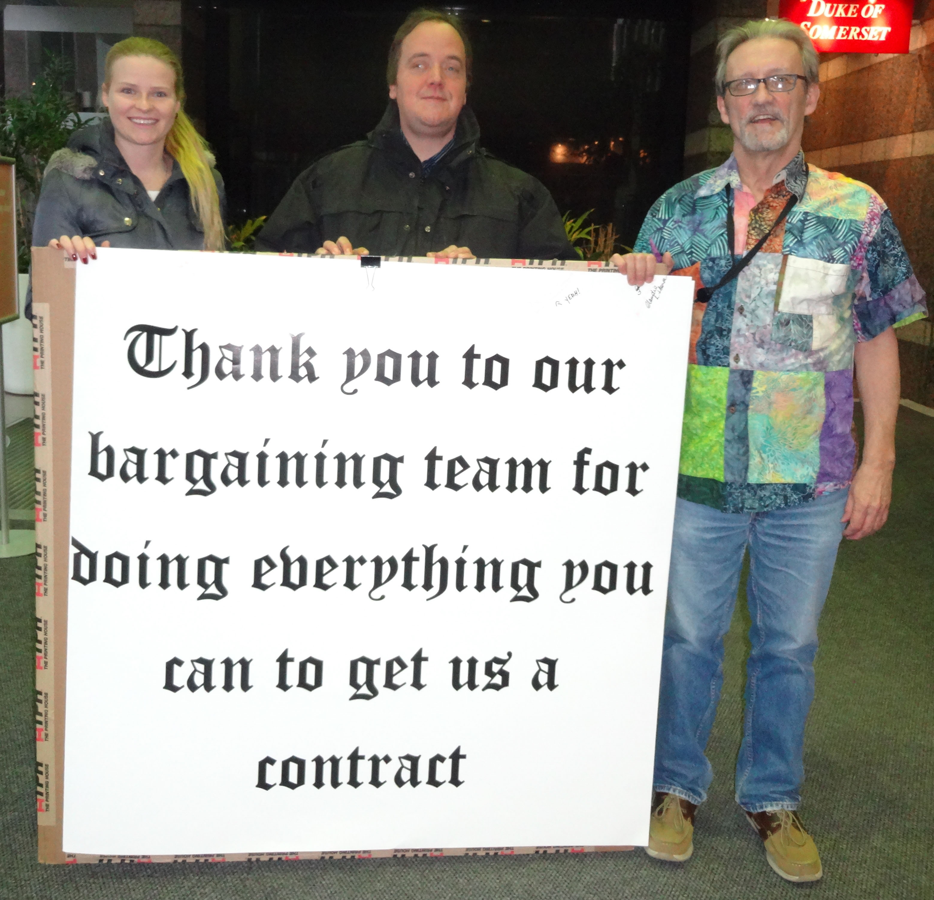 Daria Askerko, Iain MacFarlane and Jim Weir posing with the card in the lobby of the Call Centre
