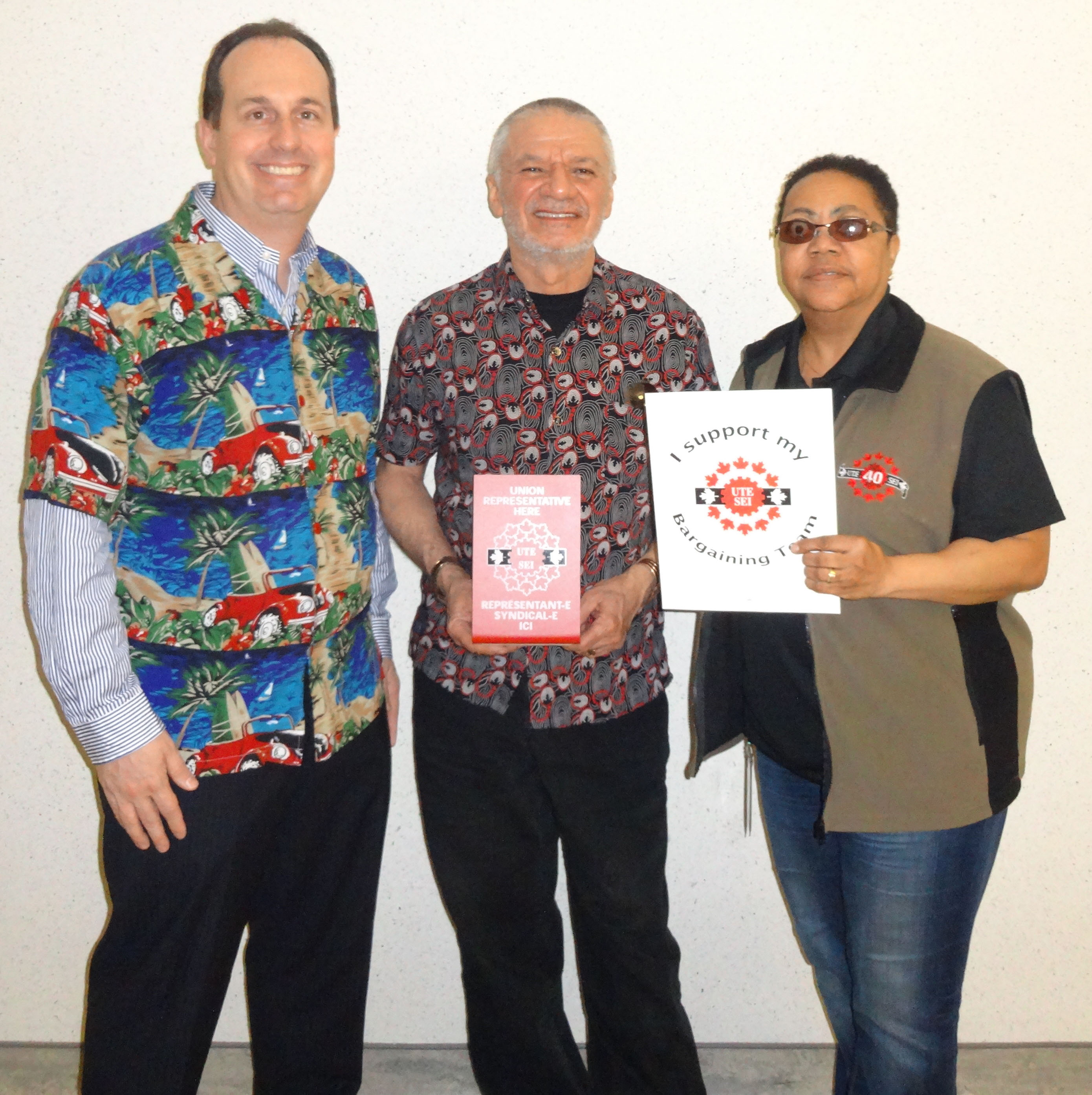 Ryan Ward, Mani Mifsud and Vona Martin posing with UTE signs and dressed up in union colours and bright colours for our "Celebration" day