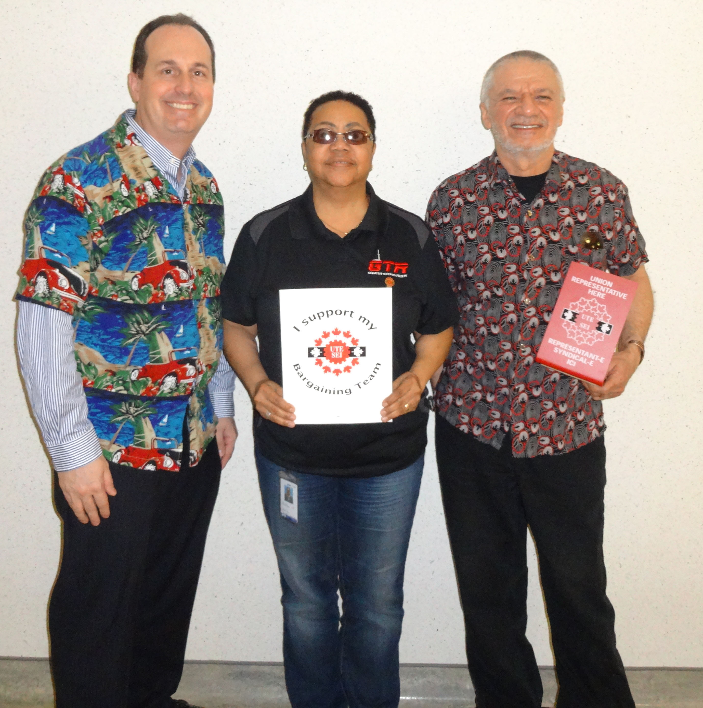 Ryan Ward, Mani Mifsud and Vona Martin posing with UTE signs and dressed up in union colours and bright colours for our "Celebration" day