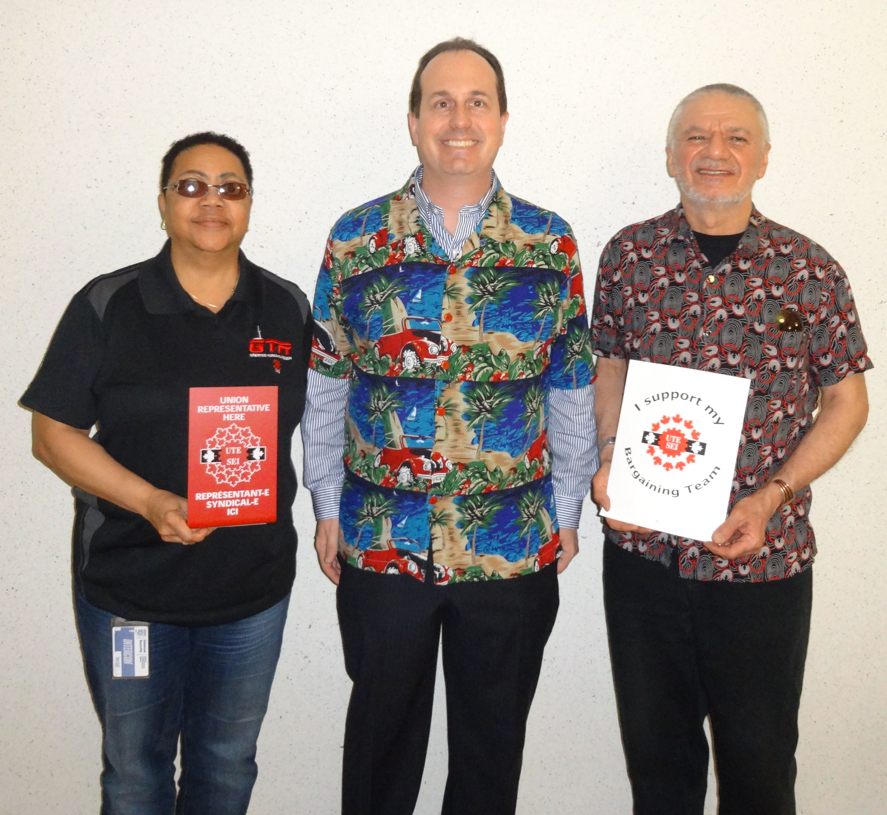 Ryan Ward, Mani Mifsud and Vona Martin posing with UTE signs and dressed up in union colours and bright colours for our "Celebration" day
